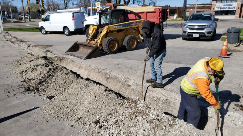 Construction crew digging a trench in a parking lot.