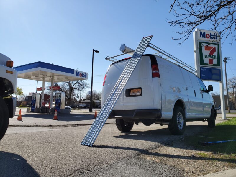 Electric conduit pipes leaning against a white van.