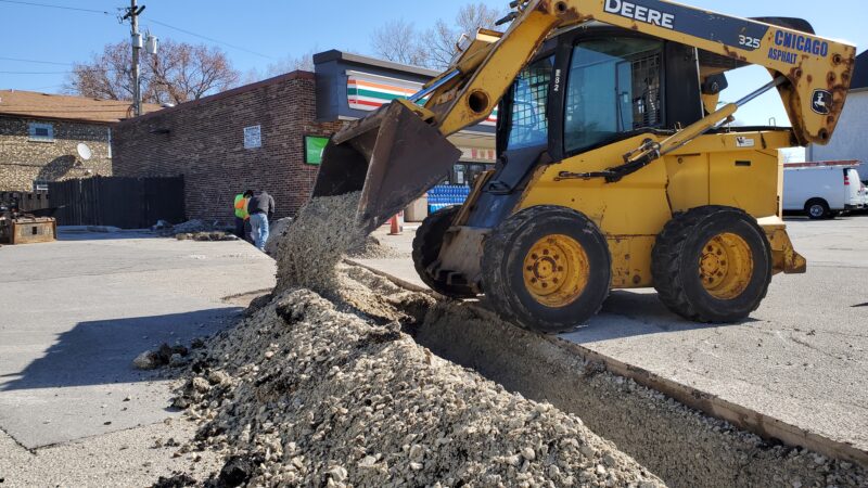 Bobcat removing dirt from a trench.