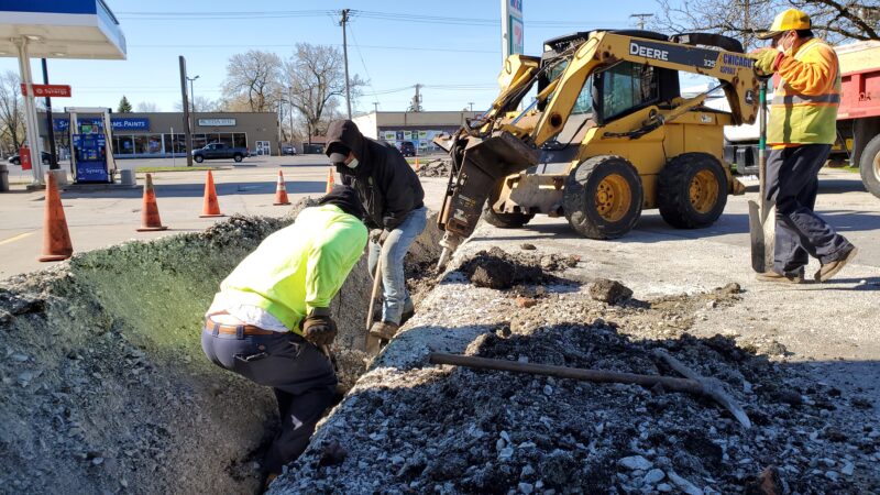 Construction crew digging a trench in a parking lot.