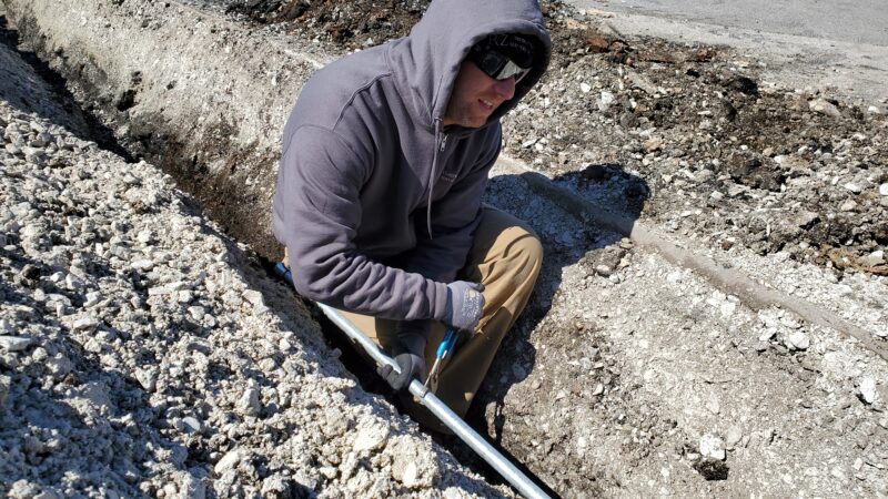 Electrician connecting pipes in a trench.
