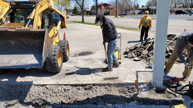 Construction workers filling in a trench.