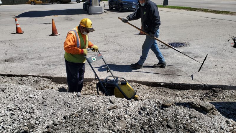 Construction workers filling in a trench.
