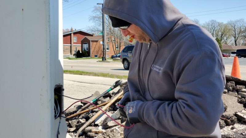Electrician wiring a sign at a gas station.