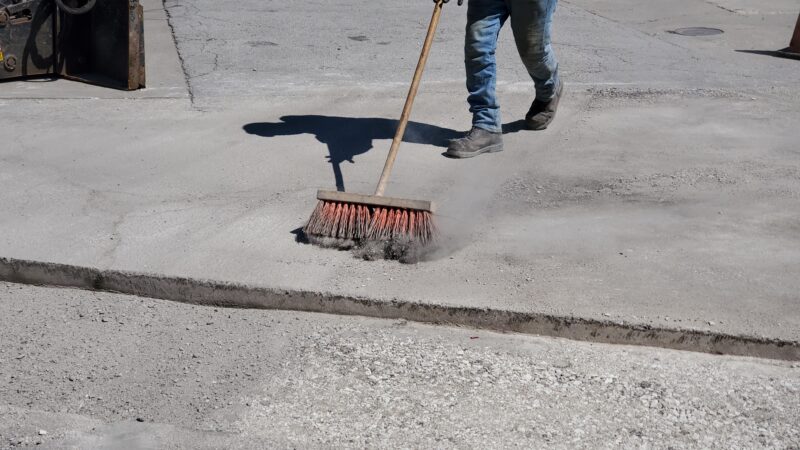 Construction worker sweeping up dirt.