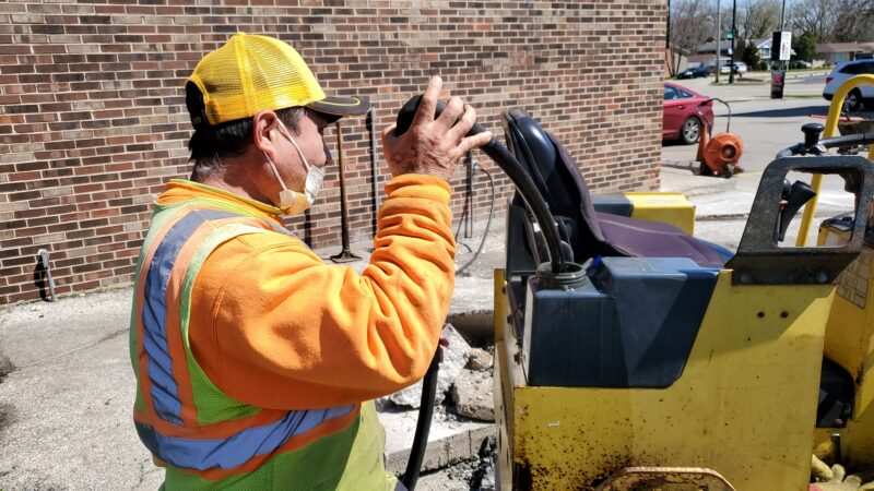 Construction worker filling a steam roller tank.