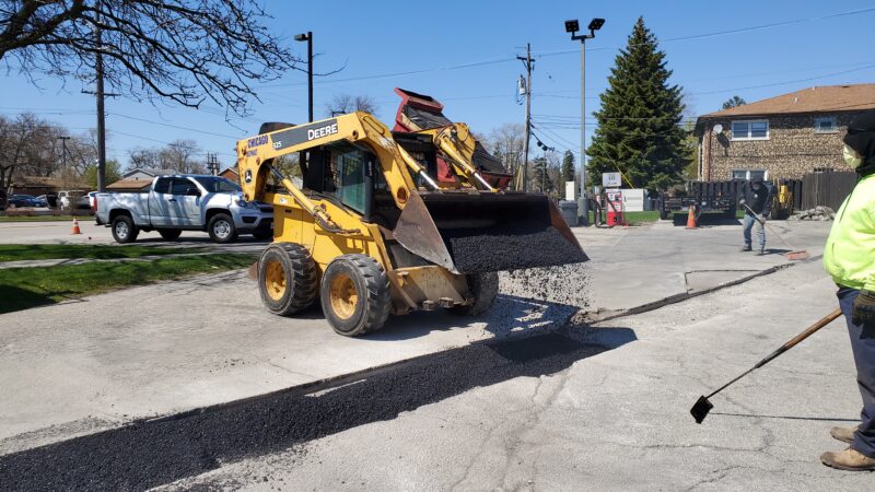 Bobcat spreading blacktop in a parking lot.