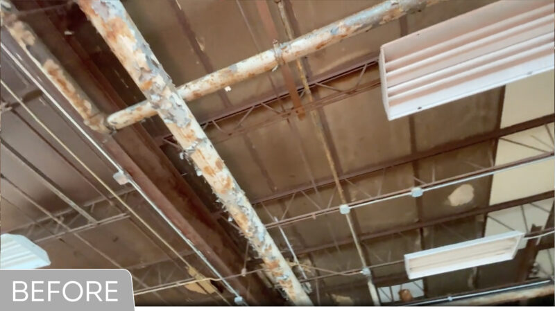 Warehouse ceiling with peeling painted pipes and fluorescent lights